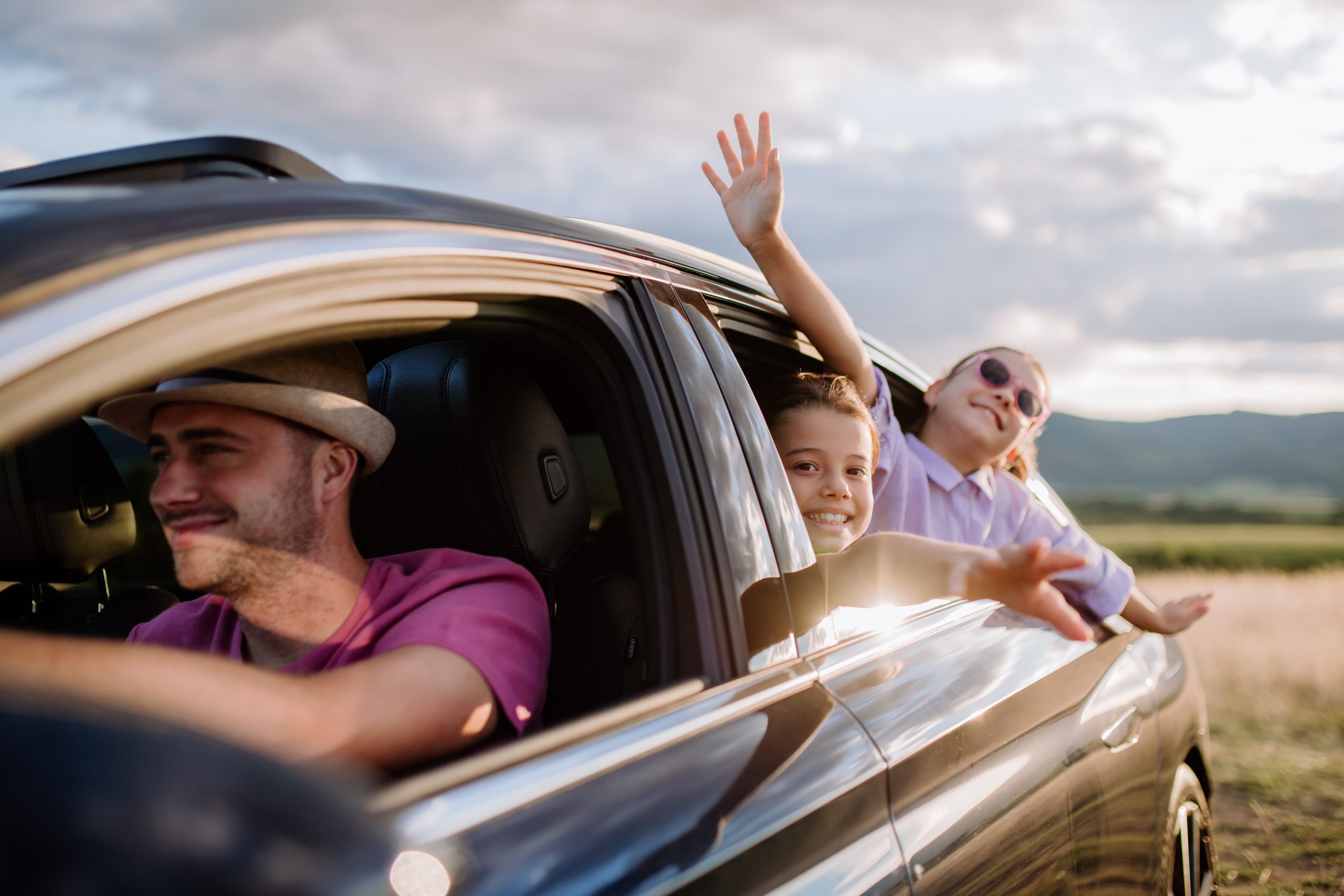 Família viajando de carro, sorrindo e aproveitando a estrada juntos em um momento de união e aventura.